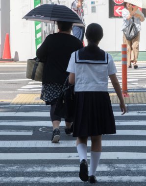 Tokyo, Japonya - 14 Temmuz 2018. Shibuya içinde karşıya okul üniformalı Japon kız.