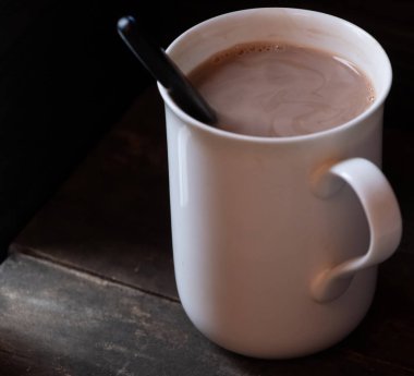 Ahşap arka plan üzerinde beyaz bir kupa sıcak çikolata