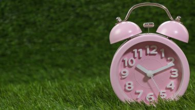 Çalar saat yeşil çimenlerin üzerinde pembe, yakın çekim