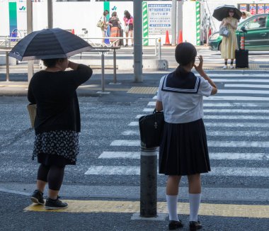 Tokyo, Japonya - 14 Temmuz 2018. Shibuya içinde karşıya okul üniformalı Japon kız.