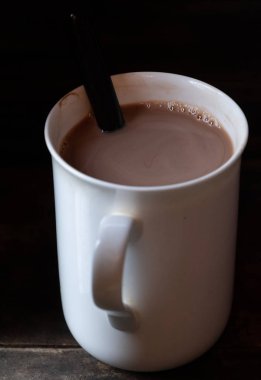 Ahşap arka plan üzerinde beyaz bir kupa sıcak çikolata