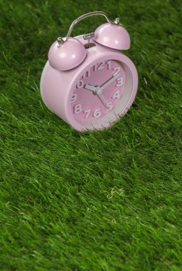 Çalar saat yeşil çimenlerin üzerinde pembe, yakın çekim