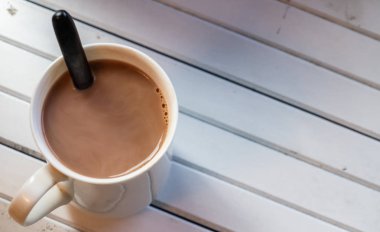 Ahşap arka plan üzerinde beyaz bir kupa sıcak çikolata