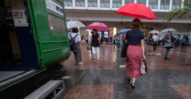 Tokyo, Japonya - 4 Temmuz 2018. Hachiko ssquare yağmurlu bir gün sırasında kırmızı şemsiye ile Japon kız.