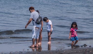 Tokyo, Japonya - 30 Nisan 2018. Enoshima Adası'nda bir plajda oynayan çocukları ile Japon baba