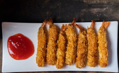 Ahşap arka plan üzerinde beyaz tabak içinde gevrek un kaplı derin kızarmış karides