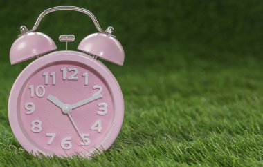 Çalar saat yeşil çimenlerin üzerinde pembe, yakın çekim
