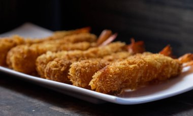 Ahşap arka plan üzerinde beyaz tabak içinde gevrek un kaplı derin kızarmış karides