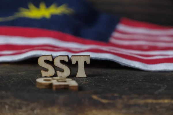 SST (Sales and Services Tax) and GST (Good and Services Tax) words with Malaysian Flag on wooden board