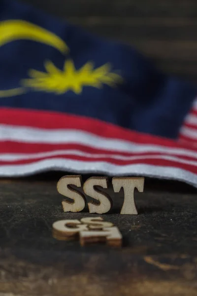 SST (Sales and Services Tax) and GST (Good and Services Tax) words with Malaysian Flag on wooden board