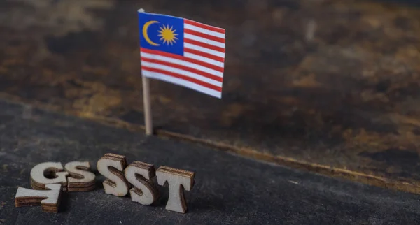 SST (Sales and Services Tax) and GST (Good and Services Tax) words with Malaysian Flag on wooden board
