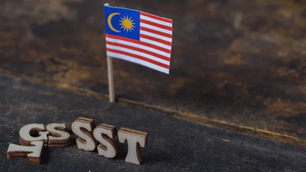 SST (Sales and Services Tax) and GST (Good and Services Tax) words with Malaysian Flag on wooden board