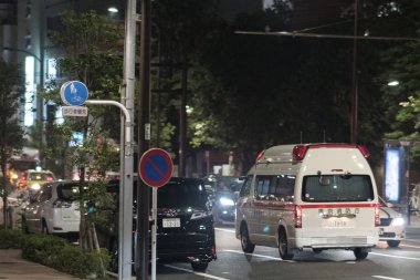 TOKYO, JAPAN - AUGUST 3RD, 2018. Ambulance emergency services rushing through the street of Tokyo at night. clipart