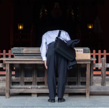 FUKUOKA, JAPAN - AUGUST 5TH, 2018.  Worshipper praying at the Chikuzen Ichinomiya Sumiyoshi Shrine. clipart