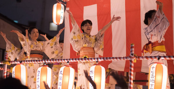 TOKYO, JAPAN - AUGUST 12TH, 2018. Dancers in traditional yukata dancing on the stage at the Bon Odori celebration in Shimokitazawa neighborhood at night.