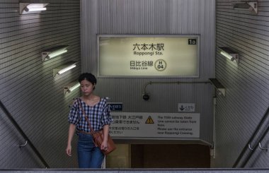 TOKYO, JAPAN - AUGUST 20TH, 2018.  Japanese girl exiting Roppongi subway station. clipart
