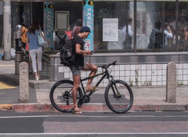 Tokyo, Japonya - 19 Ağustos 2018. Adam ile smartphone Shibuya içinde karşıdan karşıya için bekleyen bir bisiklet sürme.