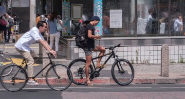 Tokyo, Japonya - 19 Ağustos 2018. Adam ile smartphone Shibuya içinde karşıdan karşıya için bekleyen bir bisiklet sürme.