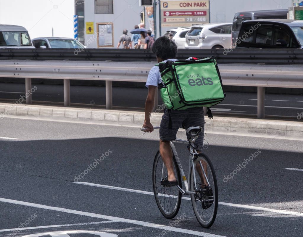 TOKYO, JAPAN - AUGUST 20TH, 2018. Uber Eat rider cycling in the street of Roppongi.