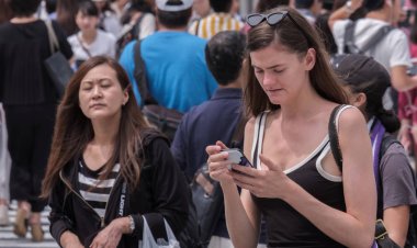 Tokyo, Japonya - 19 Ağustos 2018. Kadın turist ile karşıya Shibuya içinde smartphone.