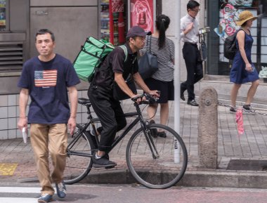 Tokyo, Japonya - 19 Ağustos 2018. Uber yiyor binici Shibuya Caddesi Bisiklete binme.