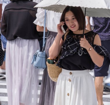 Tokyo, Japonya - 19 Ağustos 2018. Smartphone ve Shibuya içinde karşıdan karşıya bekleyen şemsiye ile Japon kız.
