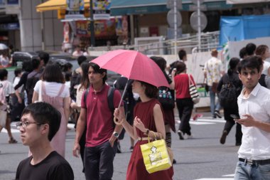 Tokyo, Japonya - 19 Ağustos 2018. Kırmızı şemsiye ve elbise sıcak bir yaz günü Shibuya içinde sırasında Japon kadınla.
