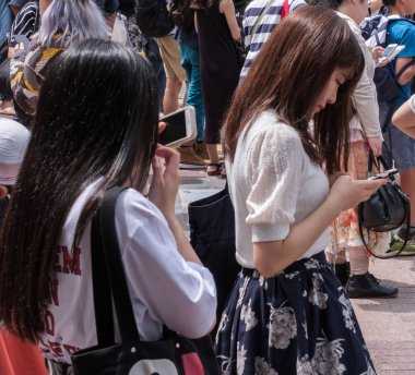Tokyo, Japonya - 19 Ağustos 2018. Shibuya içinde karşıdan karşıya bekleyen smartphone ile Japon kız.
