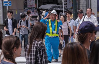 Tokyo, Japonya - 19 Ağustos 2018. Shibuya içinde karşıdan karşıya genel bir bekleyen yaşlı inşaat işçisi.