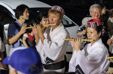 Tokyo, Japonya - 19 Ağustos 2018. Geleneksel shinobue flüt eşlik eden dans topluluğu Shimokitazawa Awa Odori Festivali sırasında sokakta oynayan kadın müzisyen.