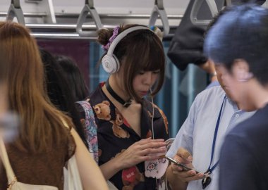 Tokyo, Japonya - 30th Ağustos 2018. Kadın yolcu Japonya demiryolu Yamanote trende commuting sırasında kulaklık için dinleme.