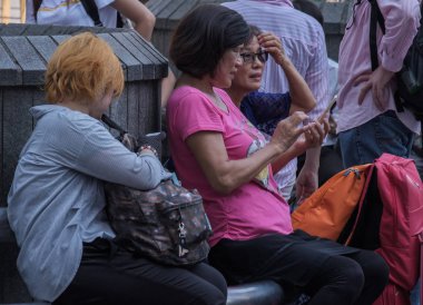 Tokyo, Japonya - 30th Ağustos 2018. Shibuya Hachiko Meydanı'nda bir bankta oturan kadın Asya turist bir grup.