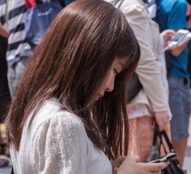 Tokyo, Japonya - 19 Ağustos 2018. Shibuya içinde karşıdan karşıya bekleyen smartphone ile Japon kız.