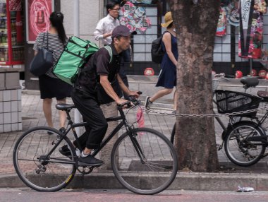 Tokyo, Japonya - 19 Ağustos 2018. Uber yiyor binici Shibuya Caddesi Bisiklete binme.