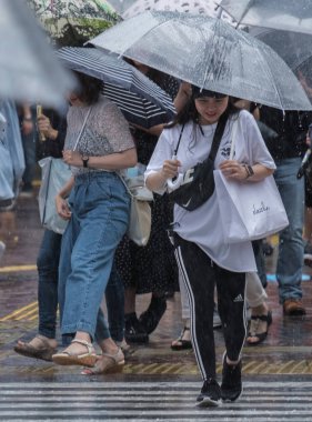 Tokyo, Japonya - 29 Temmuz 2018. Shibuya içinde yağmurlu tayfun sezonunda şemsiye ile Japon kız.
