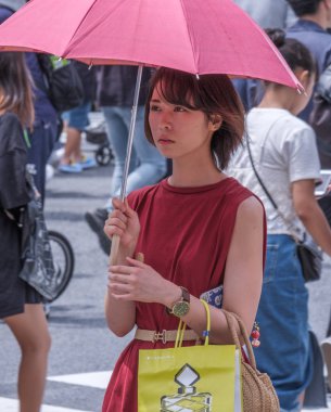 Tokyo, Japonya - 19 Ağustos 2018. Kırmızı şemsiye ve elbise sıcak bir yaz günü Shibuya içinde sırasında Japon kadınla.