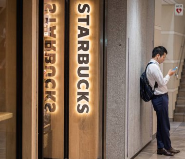 Tokyo, Japonya - 23 Haziran 2018. Starbucks kahvesi Shibuya içinde dışarıda bekleyen smarphone adamla