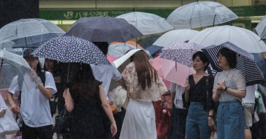 Tokyo, Japonya - 29 Temmuz 2018. Yağmurlu tayfun sezonu boyunca şemsiye ile karşıdan karşıya için bekleyen kişi.