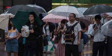 Tokyo, Japonya - 29 Temmuz 2018. Yağmurlu tayfun sezonu boyunca şemsiye ile karşıdan karşıya için bekleyen kişi.
