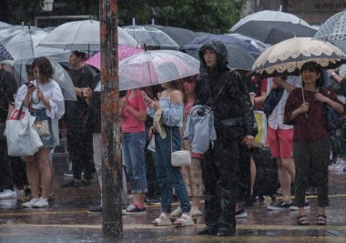 Tokyo, Japonya - 29 Temmuz 2018. Yağmurlu tayfun sezonu boyunca şemsiye ile karşıdan karşıya için bekleyen kişi.