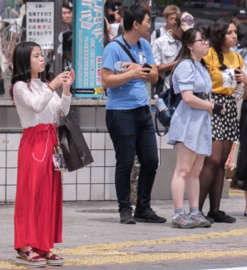 Tokyo, Japonya - 19 Ağustos 2018. Shibuya içinde karşıdan karşıya bekleyen smartphone ile Japon kız.