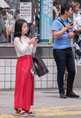 Tokyo, Japonya - 19 Ağustos 2018. Shibuya içinde karşıdan karşıya bekleyen smartphone ile Japon kız.