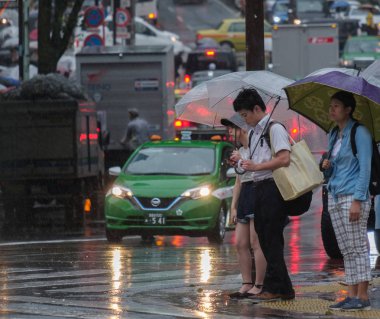 Tokyo, Japonya - 29 Temmuz 2018. Yağmurlu tayfun sezonu boyunca şemsiye ile karşıdan karşıya için bekleyen kişi.