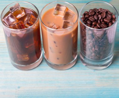 Ahşap arka plan üzerinde siyah kahve, soğuk latte ve fasulye buzlu