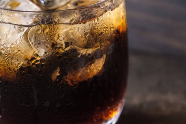 Ahşap masa üstü buz ile bir bardak kola içecek yakın çekim