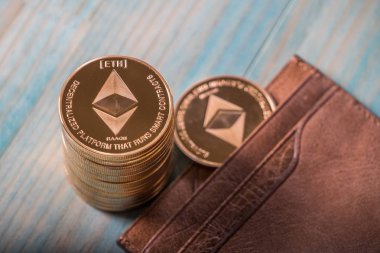 Ahşap masa üzerinde deri cüzdan ile Ethereum sikkeler