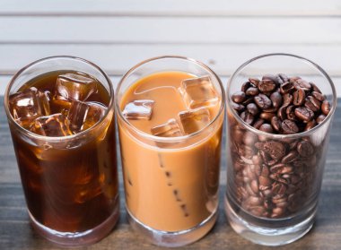 Ahşap arka plan üzerinde siyah kahve, soğuk latte ve fasulye buzlu