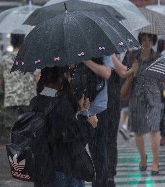 Tokyo, Japonya - 29 Temmuz 2018. Japon liseli kız yağmurlu tayfun sezonu boyunca şemsiye ile karşıya.