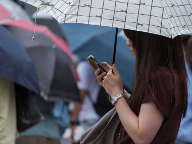 Tokyo, Japonya - 29 Temmuz 2018. Shibuya içinde yağmurlu tayfun sezonunda bir şemsiye tutan smartphone ile Japon kız.