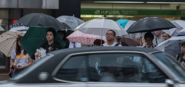 Tokyo, Japonya - 29 Temmuz 2018. Yağmurlu tayfun sezonu boyunca şemsiye ile karşıdan karşıya için bekleyen kişi.